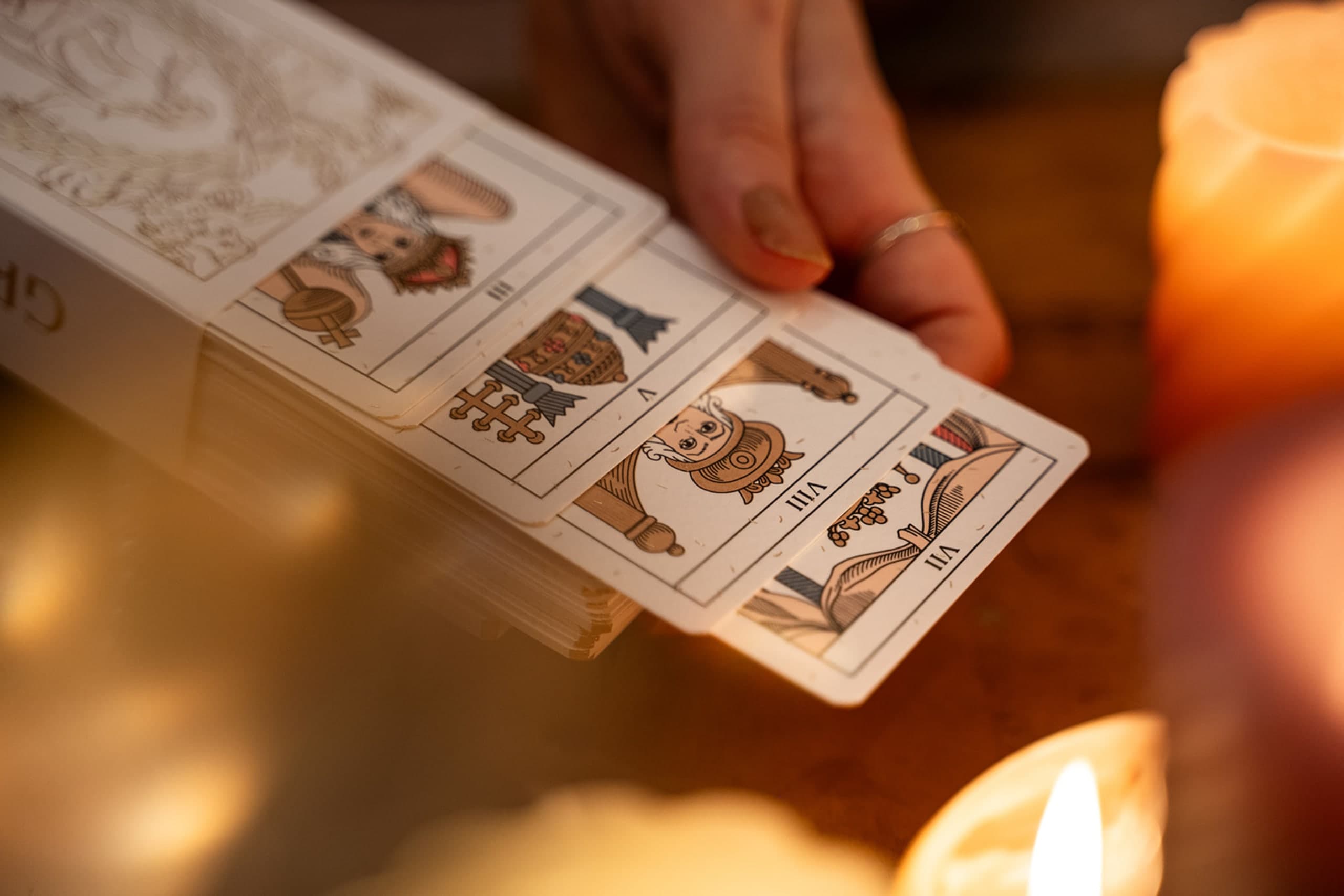 carte du Tarot de Marseille tenue à côté d'une bougie allumée