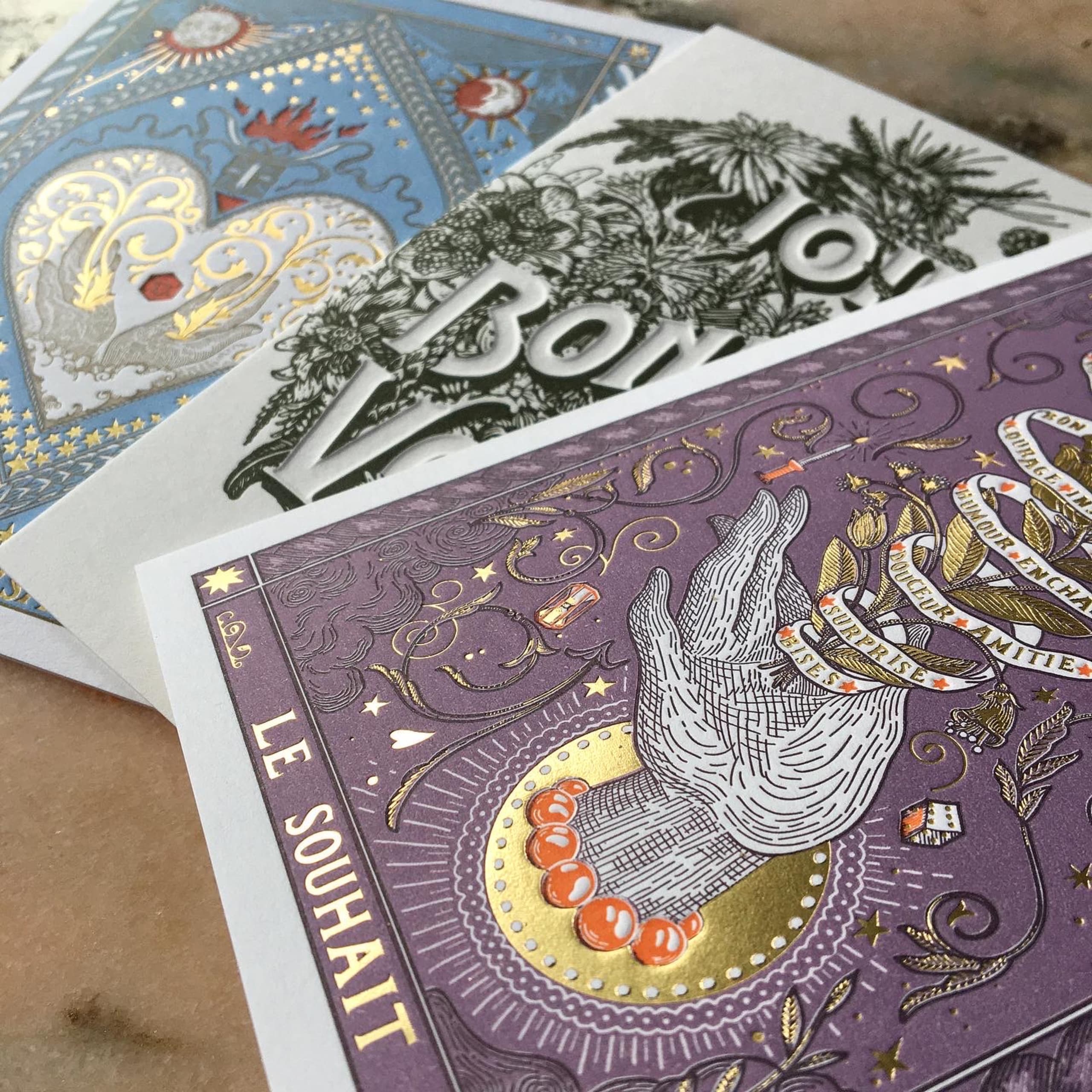 trois cartes de vœux illustrées en letterpress posées sur une surface