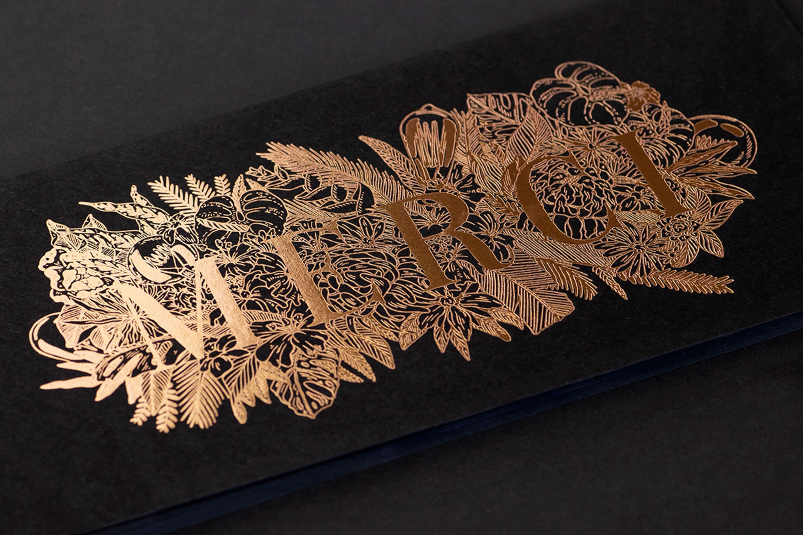 carte noire avec lettrage typographique doré « merci »